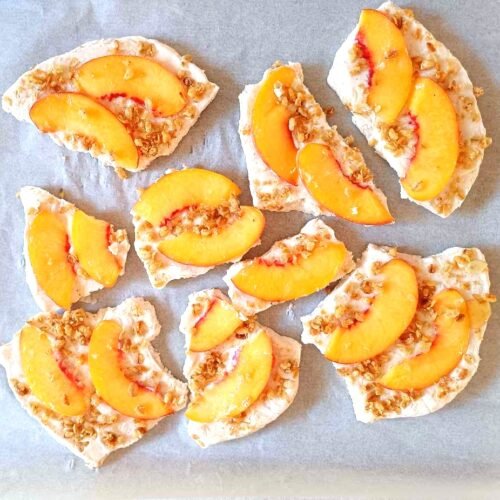 Frozen peach honey yoghurt bark broken into pieces on parchment paper